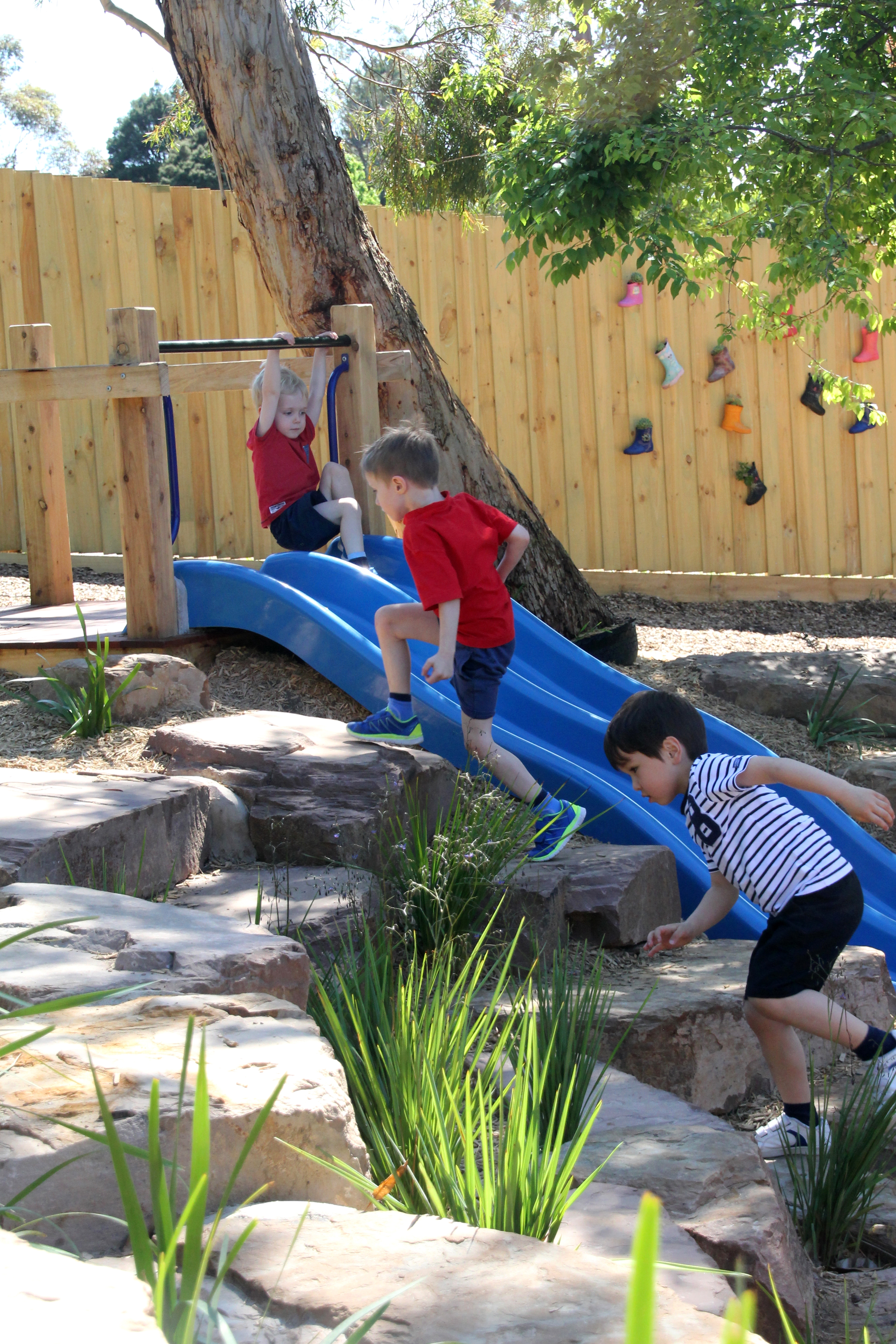 Children running up rocks and sliding down a slide