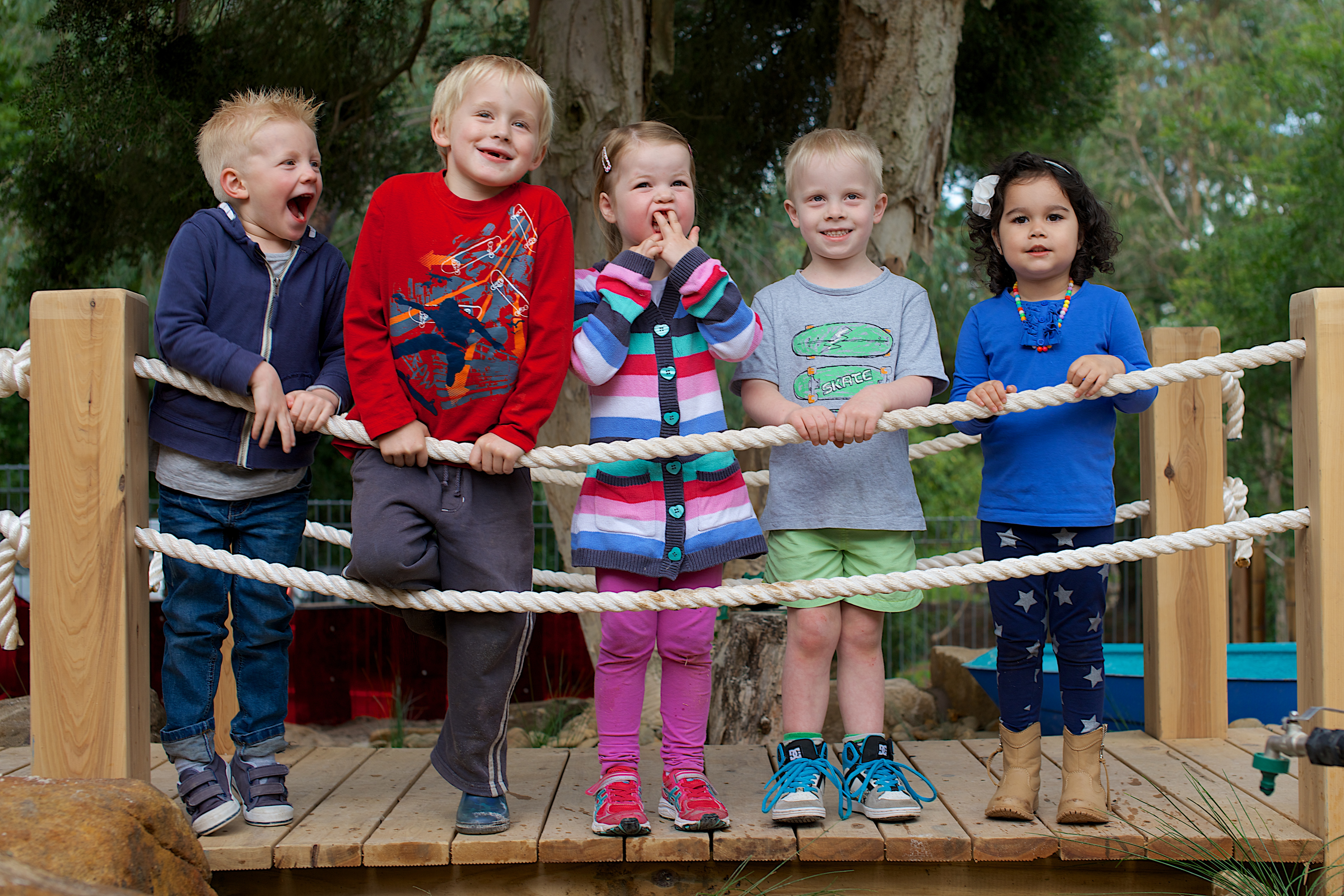 five children standing on a bridge smiling