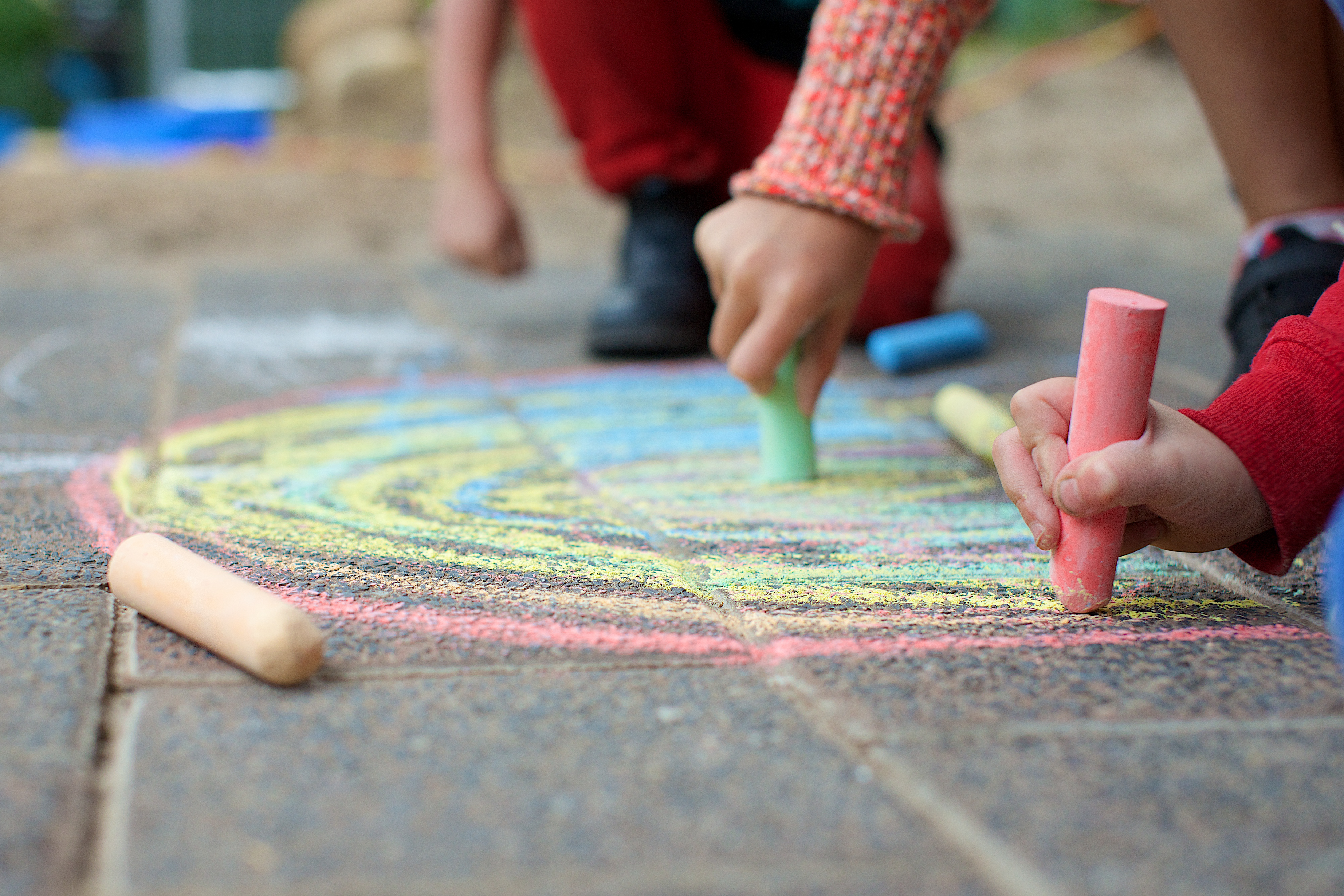 Close up of childrens hands drawing on pavers with chalk