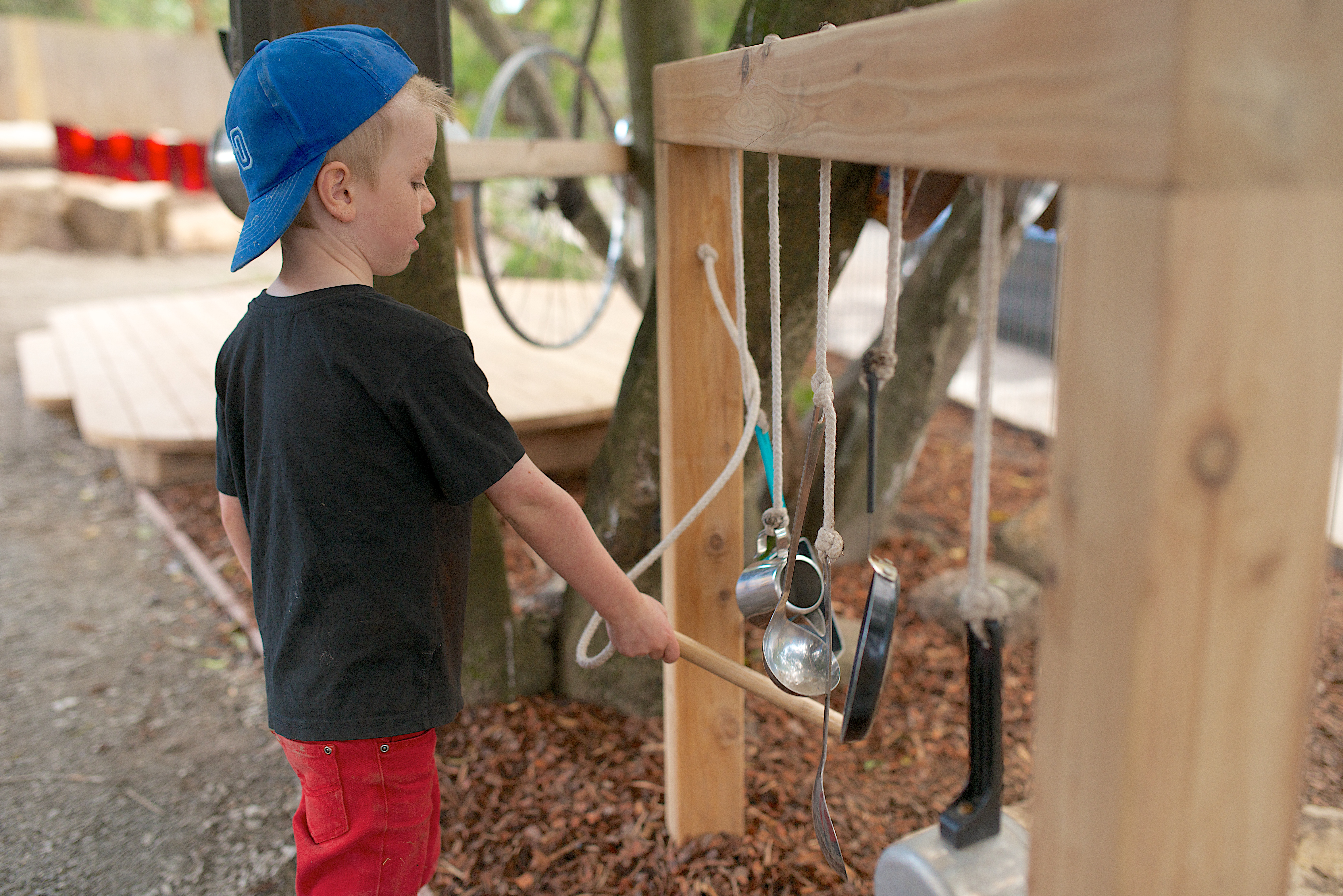 Child banging hanging pots and pans with a stick