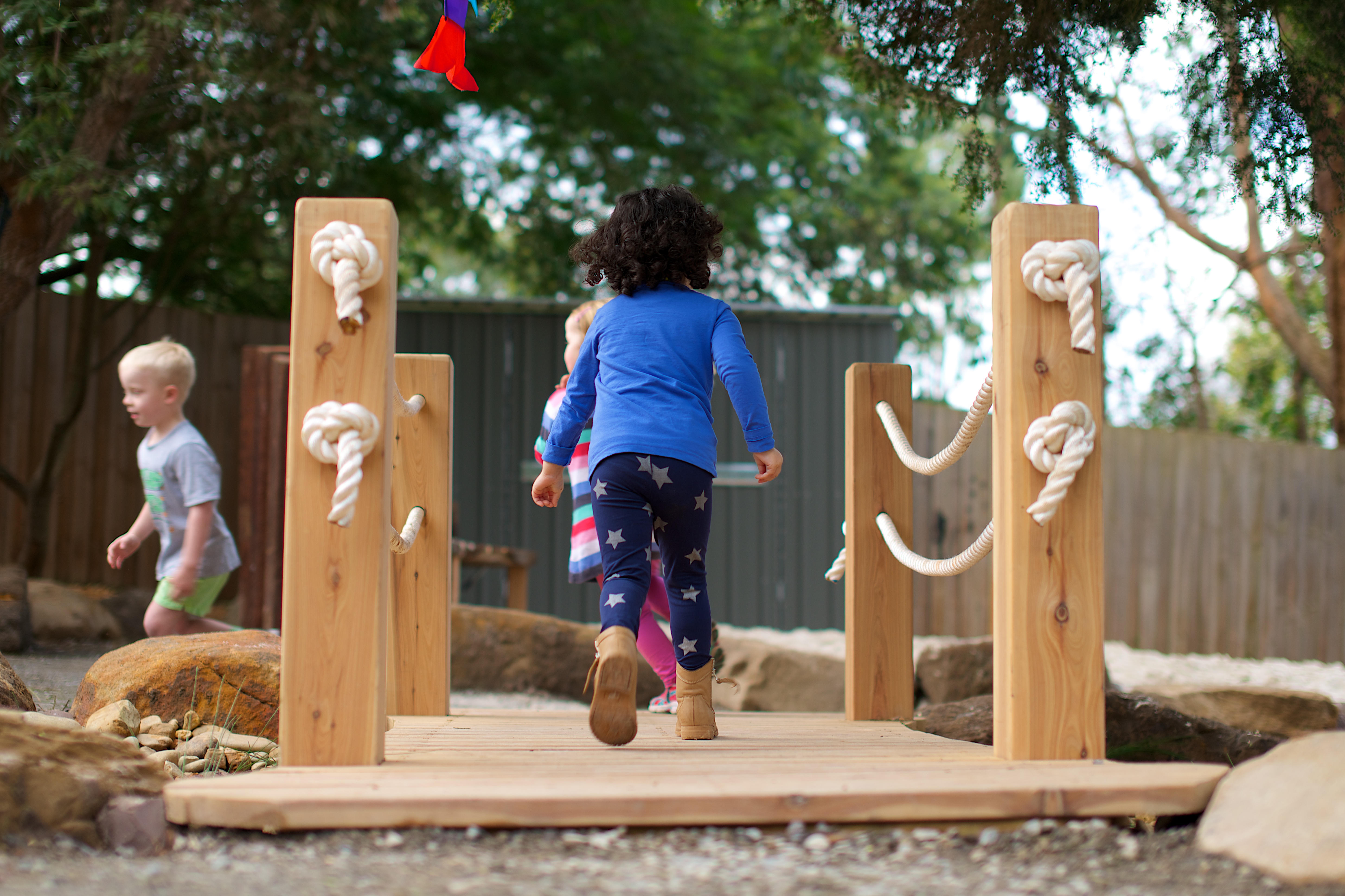 Children walking across a wooden bridge