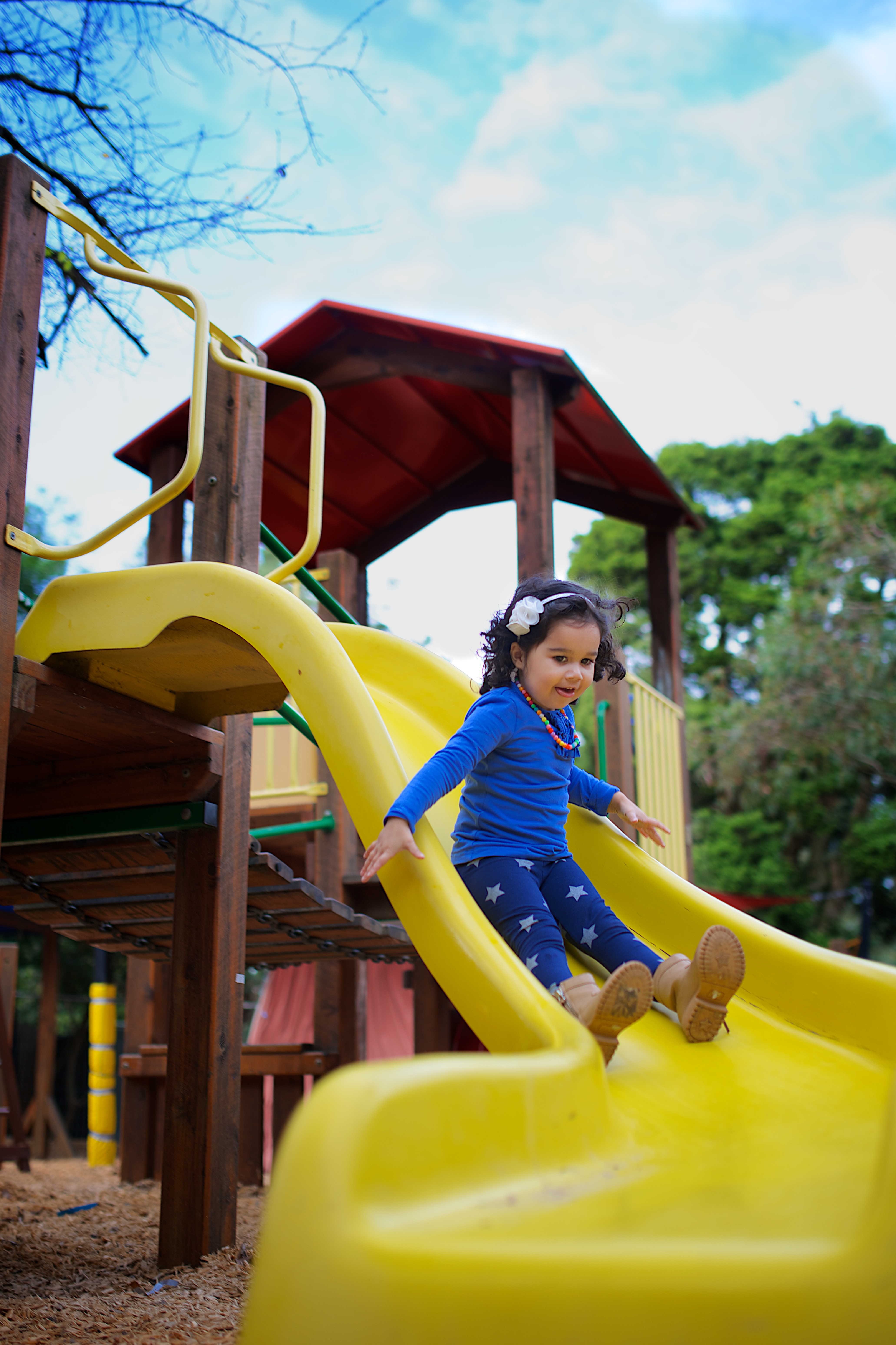 Child sliding down yellow slide